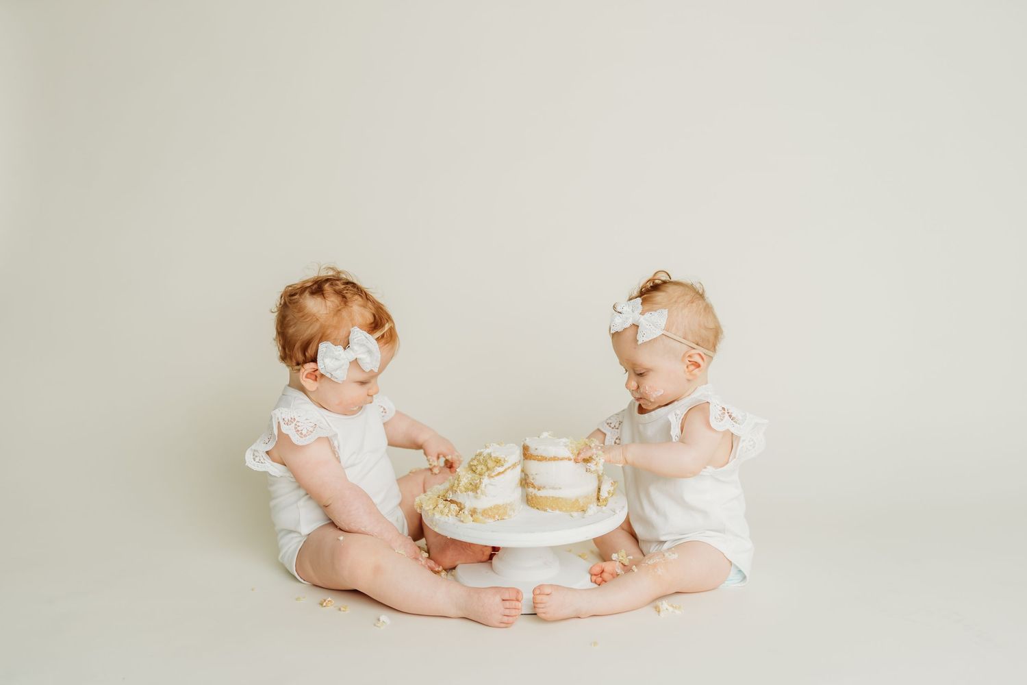Laughing baby in brown outfit with pizza box against cream background.