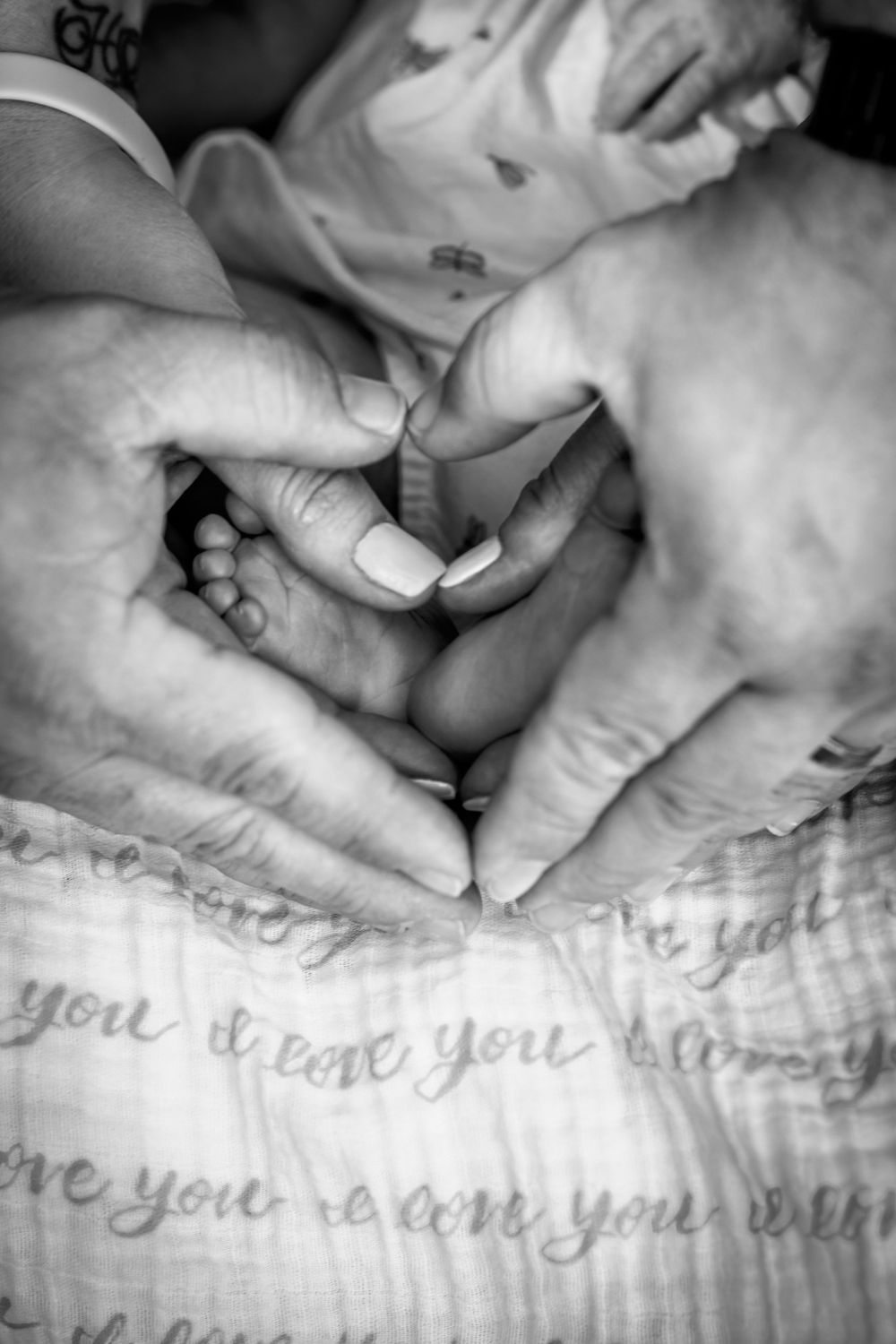 Close-up black and white image of tiny feet with text visible on a blanket below.