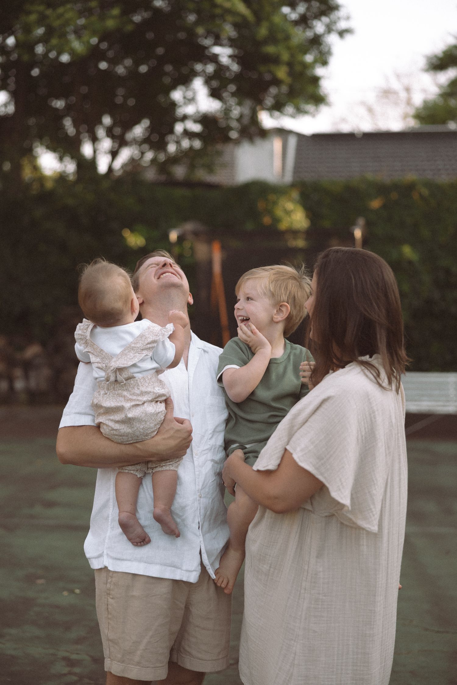 A joyful family shares candid laughter and embraces together in a backyard setting during golden hour.