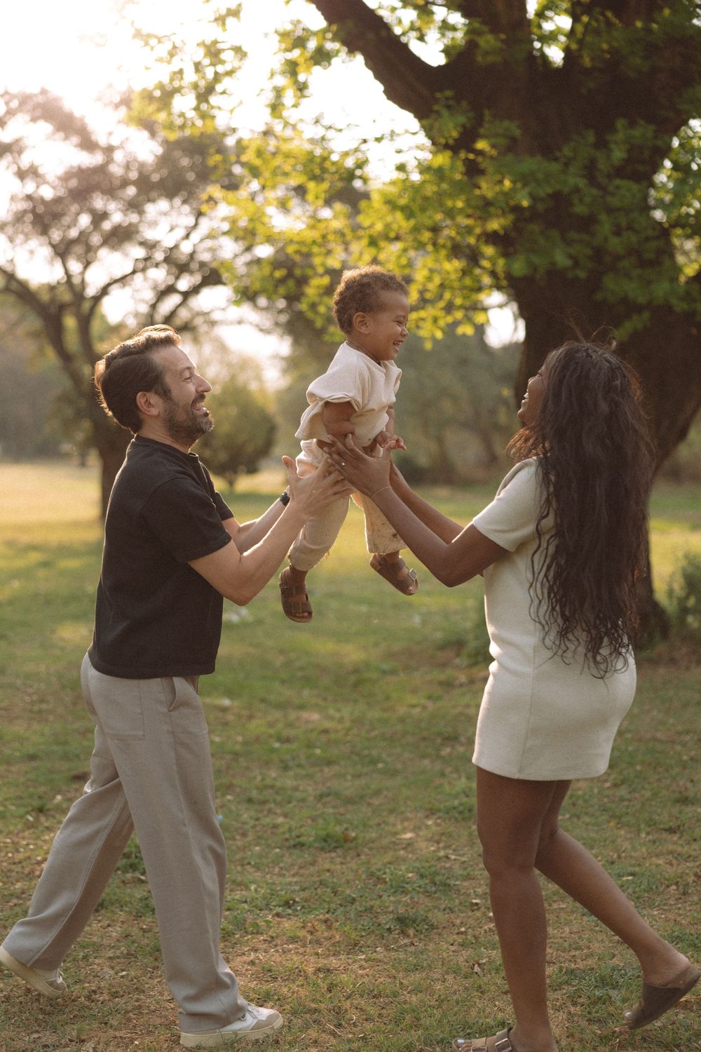 A couple dances playfully in a sunlit park during golden hour, creating a series of joyful movement shots.