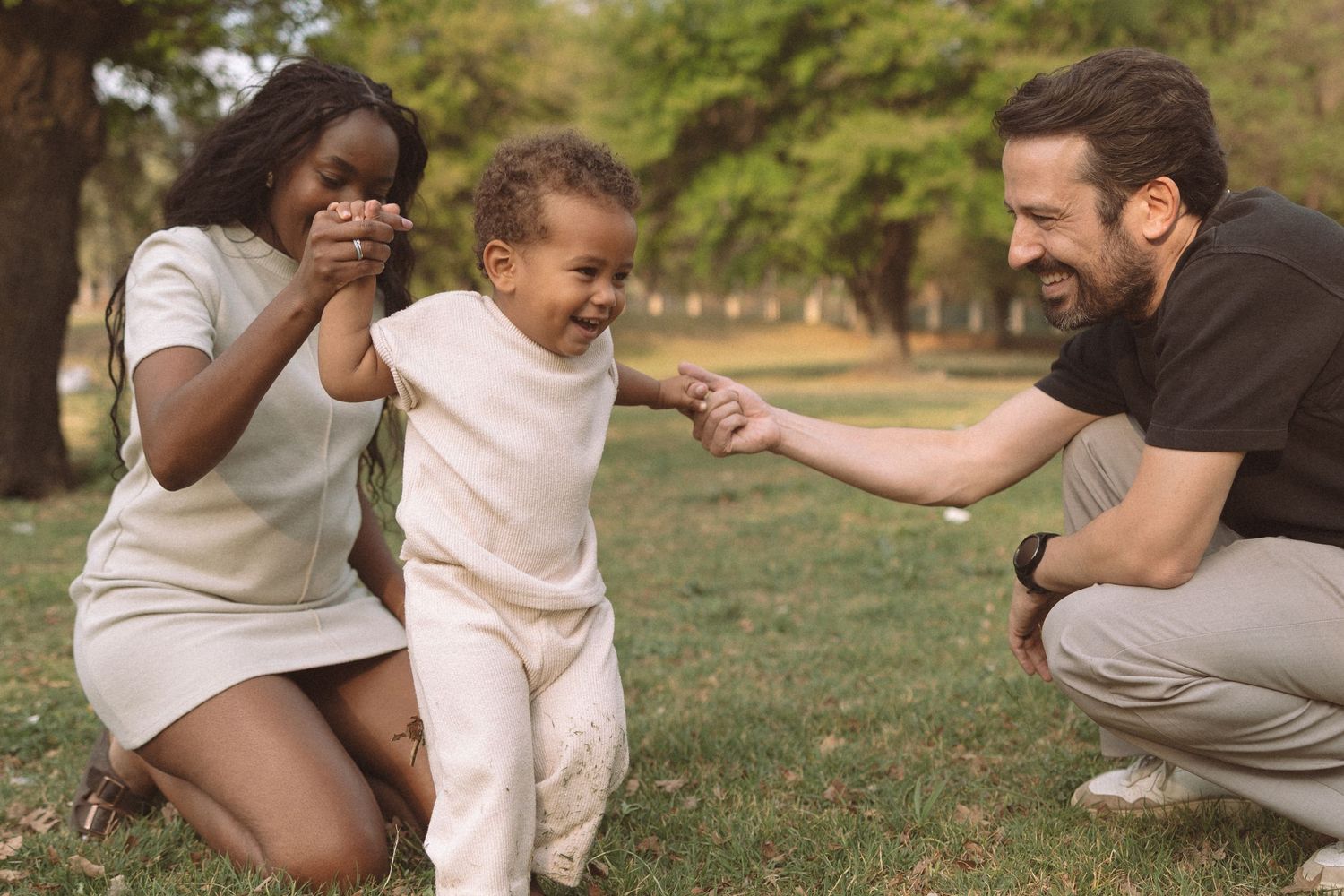 A joyful family moment outdoors as they laugh and play together in a park setting during a sunny day.