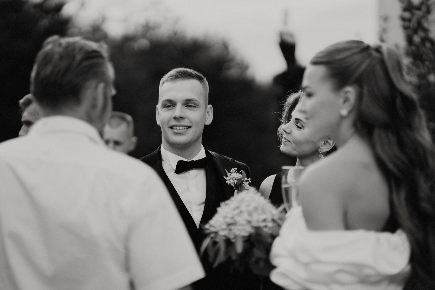 Black and white photo of wedding guests mingling at outdoor celebration.