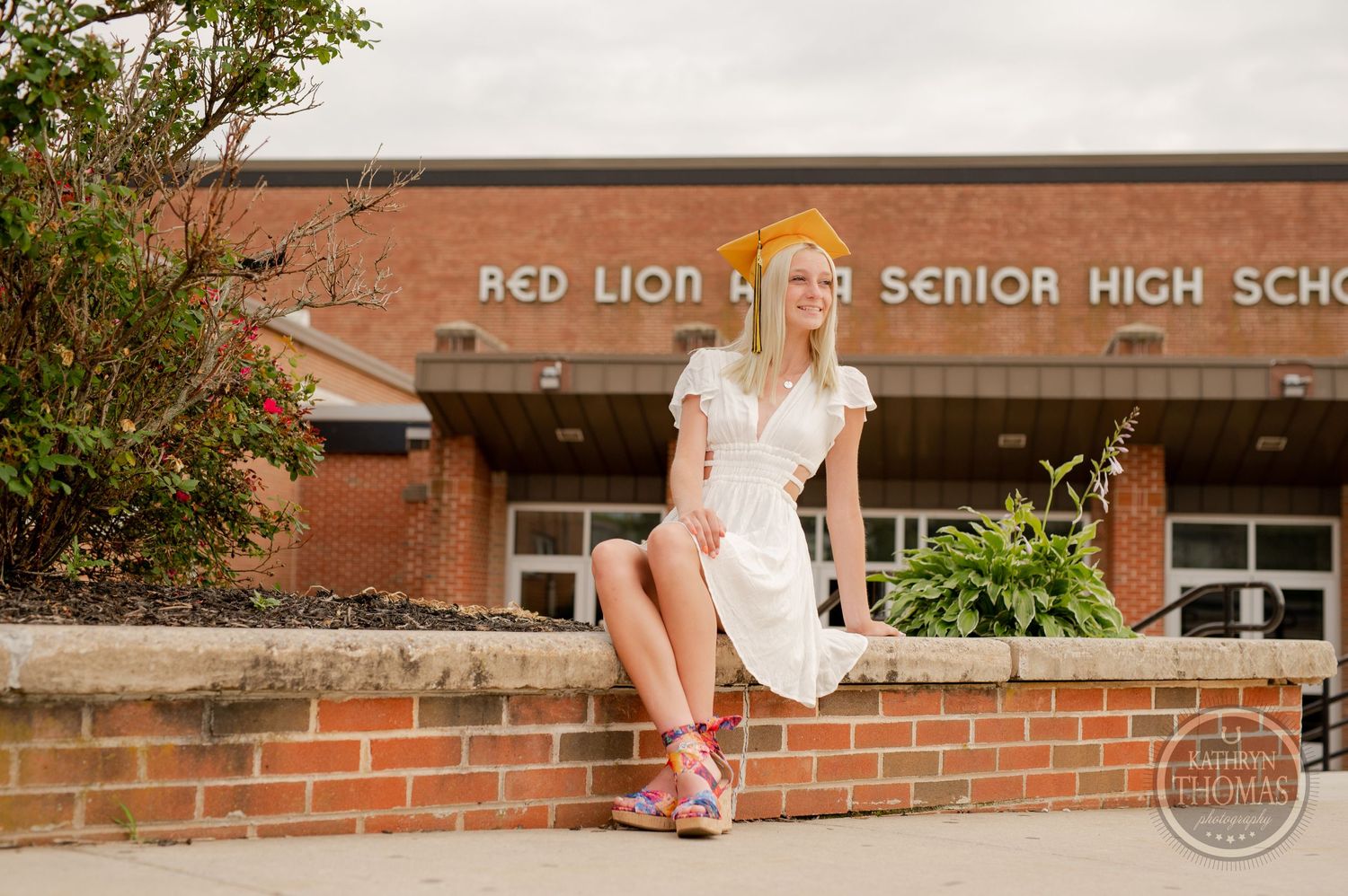 Graduate poses casually on brick wall outside Red Lion Area Senior High School.