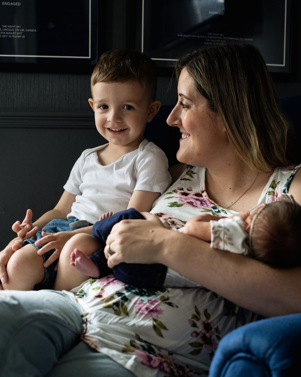 A tender family moment showing a parent in a floral shirt sitting with children in a cozy indoor setting.