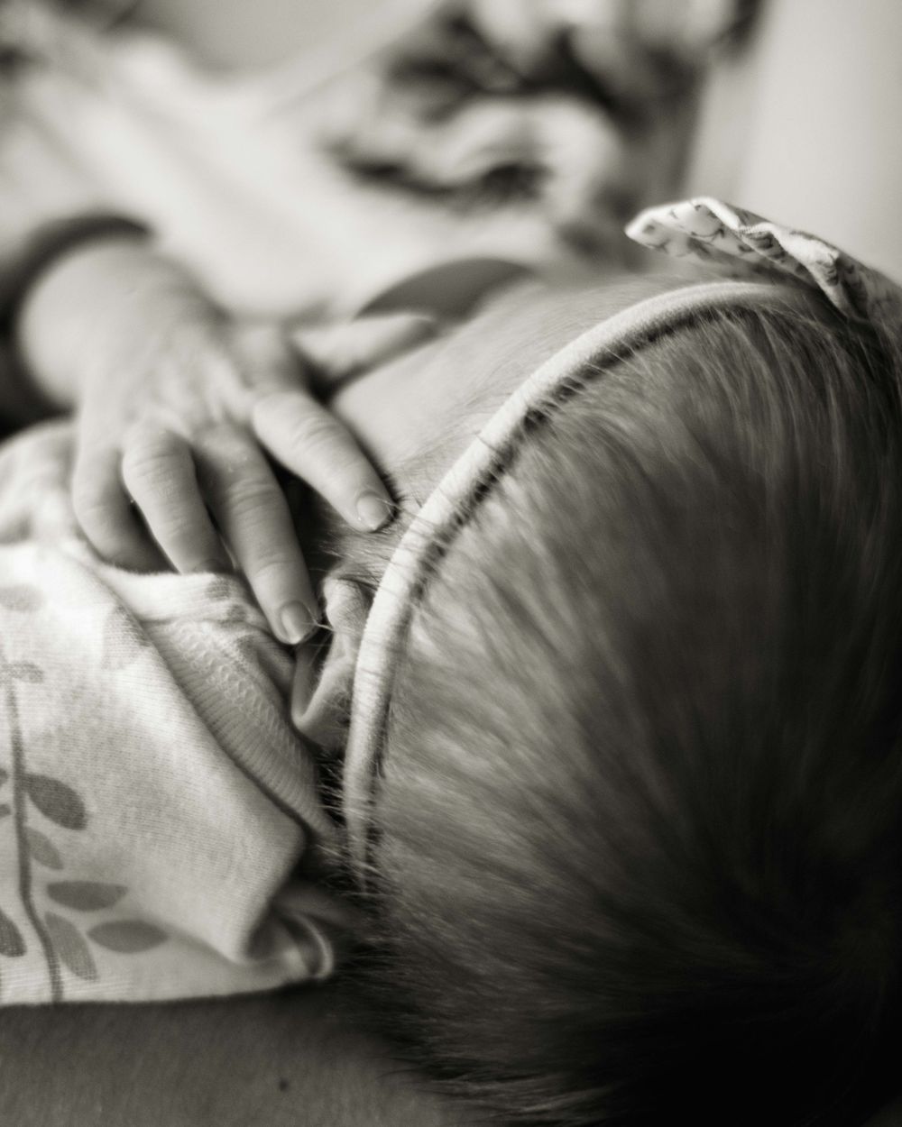 Close-up black and white detail of gentle hand resting on sleeping baby.