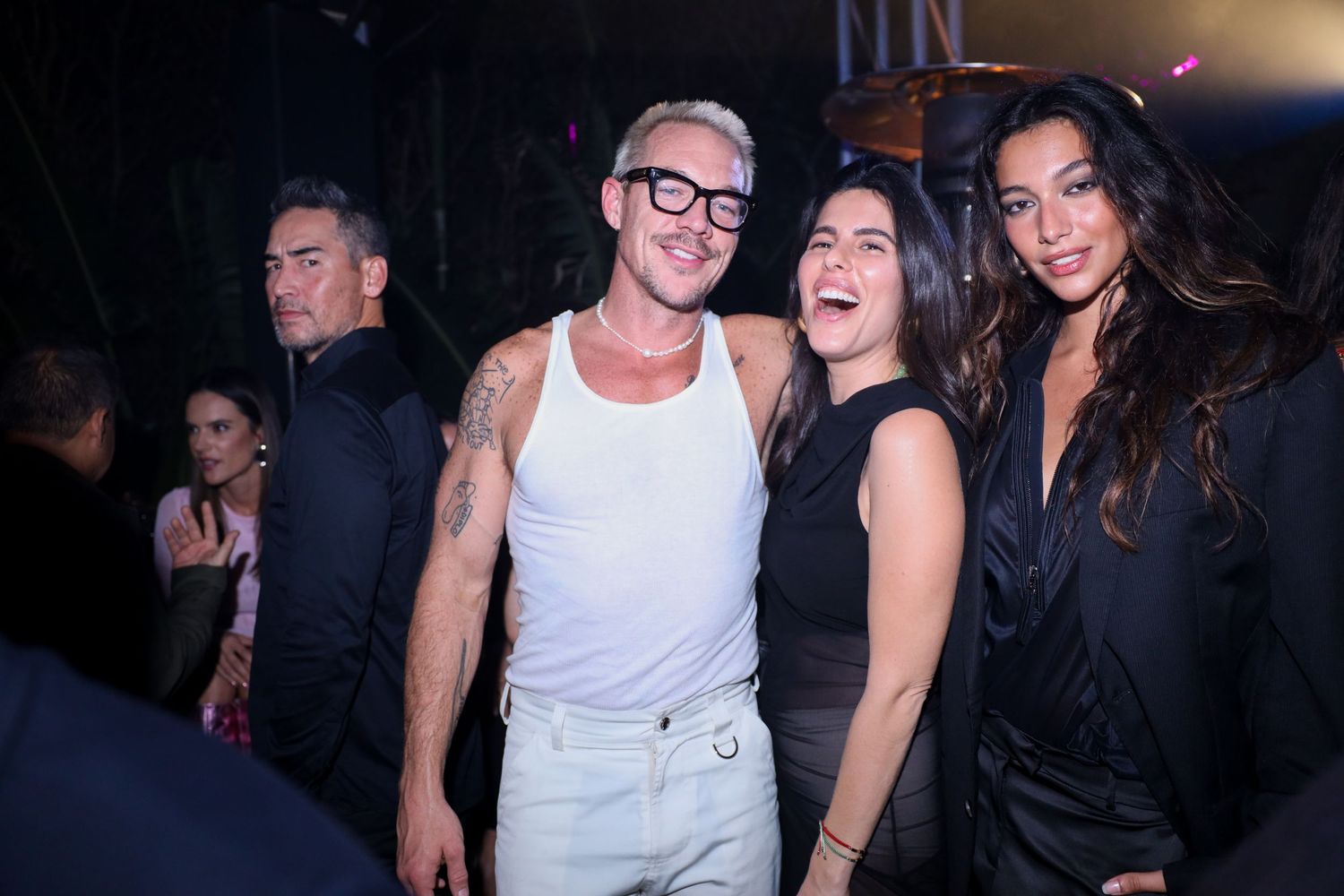 People laugh and socialize together at a dimly lit nightclub party or event.