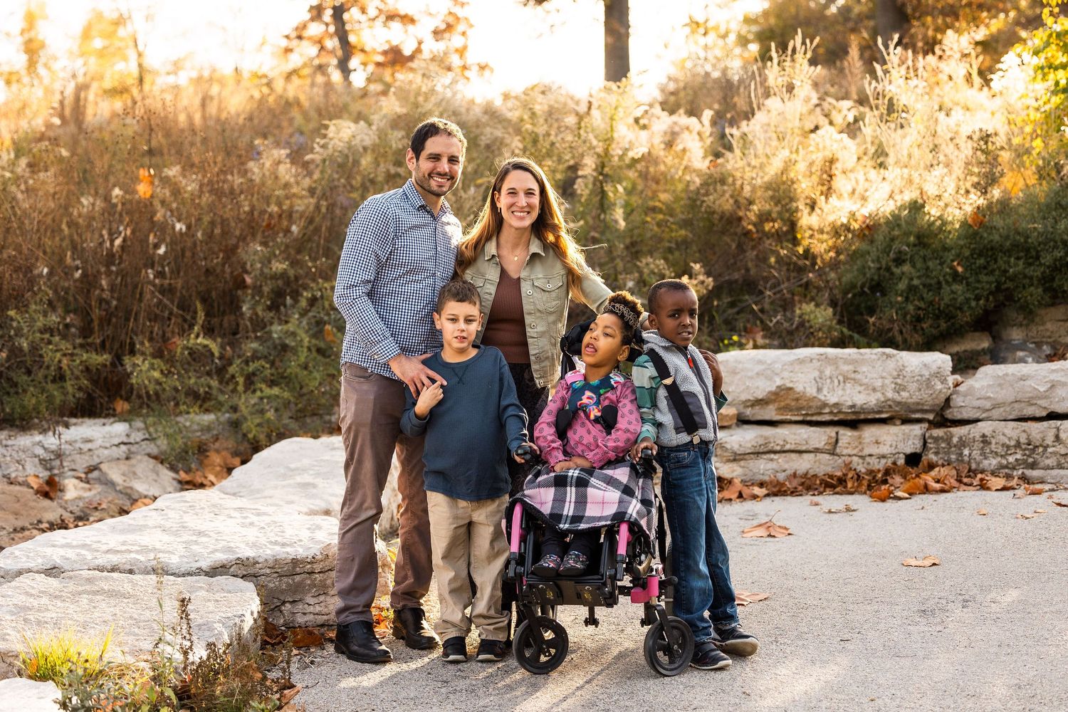 Family group walking together on scenic path during sunset with natural landscape.