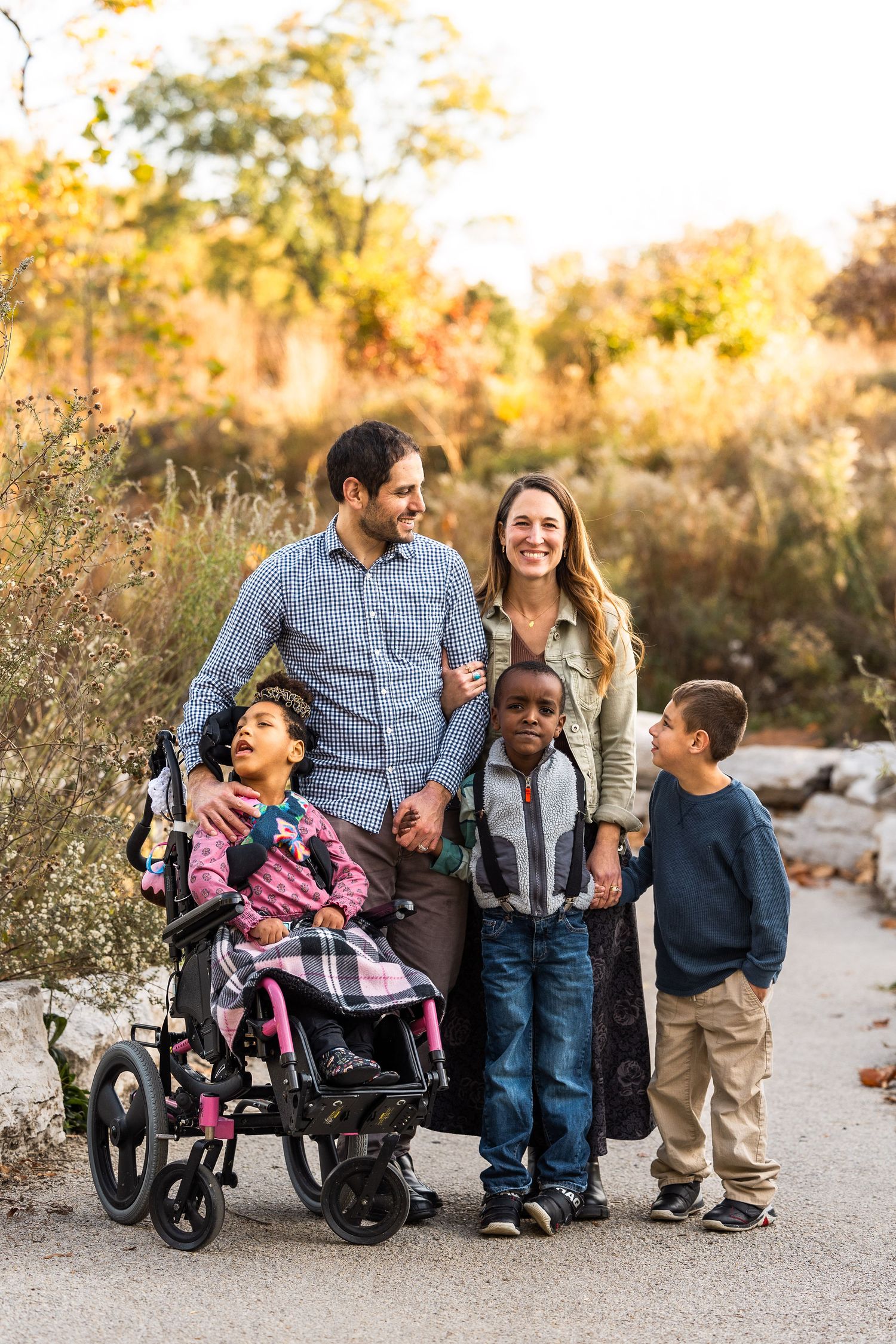 Family group photo on nature path with wheelchairs during sunset golden hour.