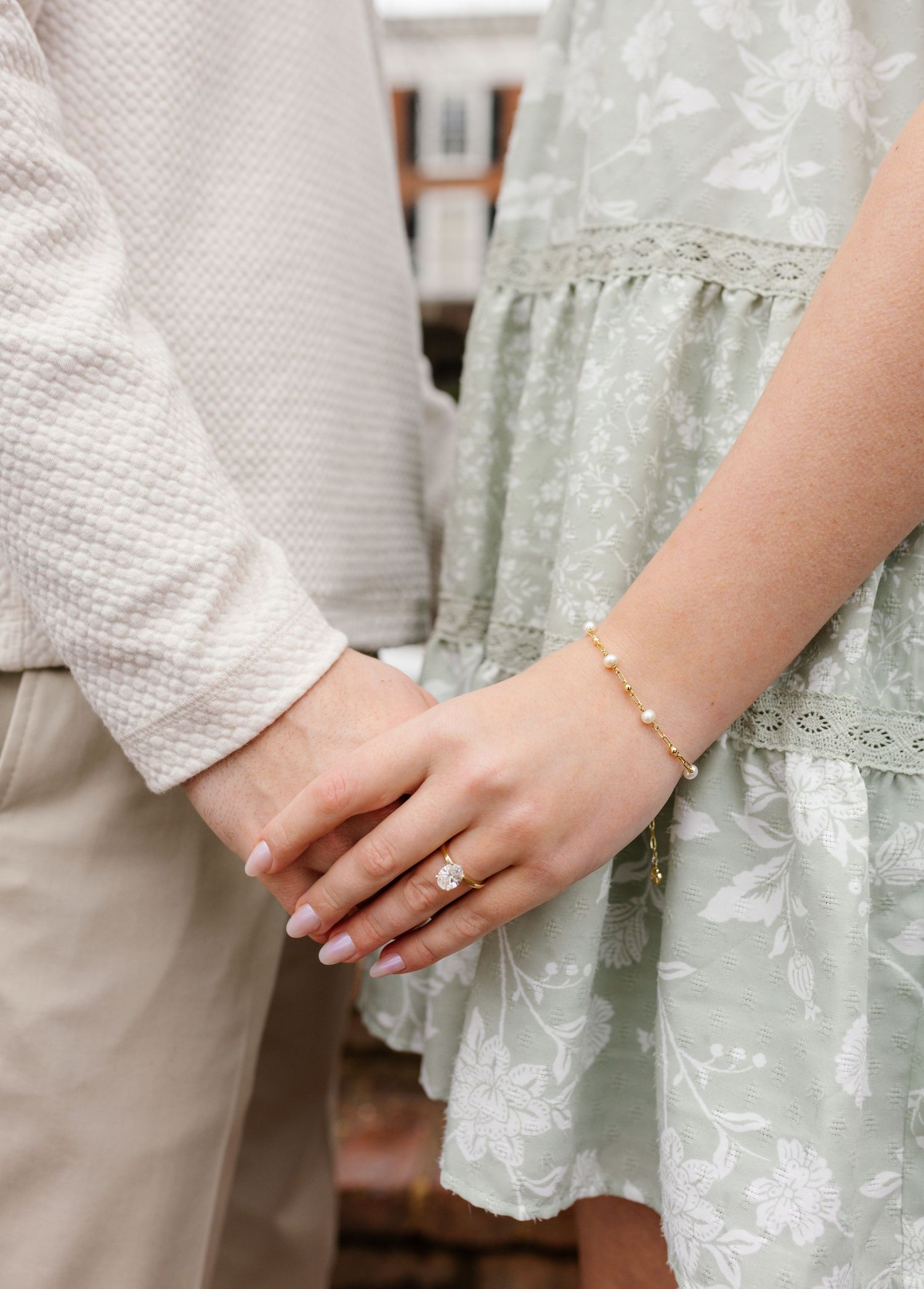 Close-up of hands showing an engagement ring against a dark background.