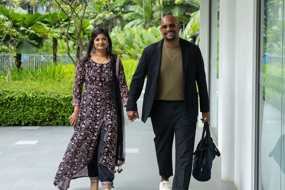 Couple walking together along a modern building exterior with greenery.