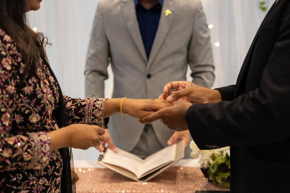 Exchange of rings during intimate wedding ceremony with officiant present.