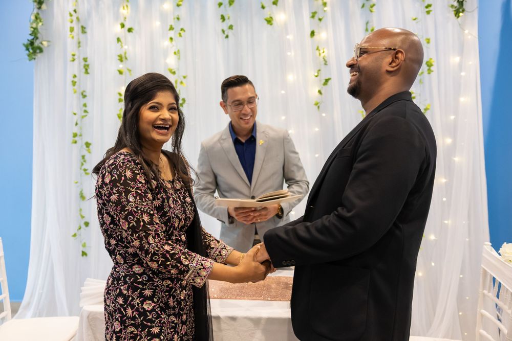 Joyful wedding ceremony moment with couple and officiant at decorated altar.