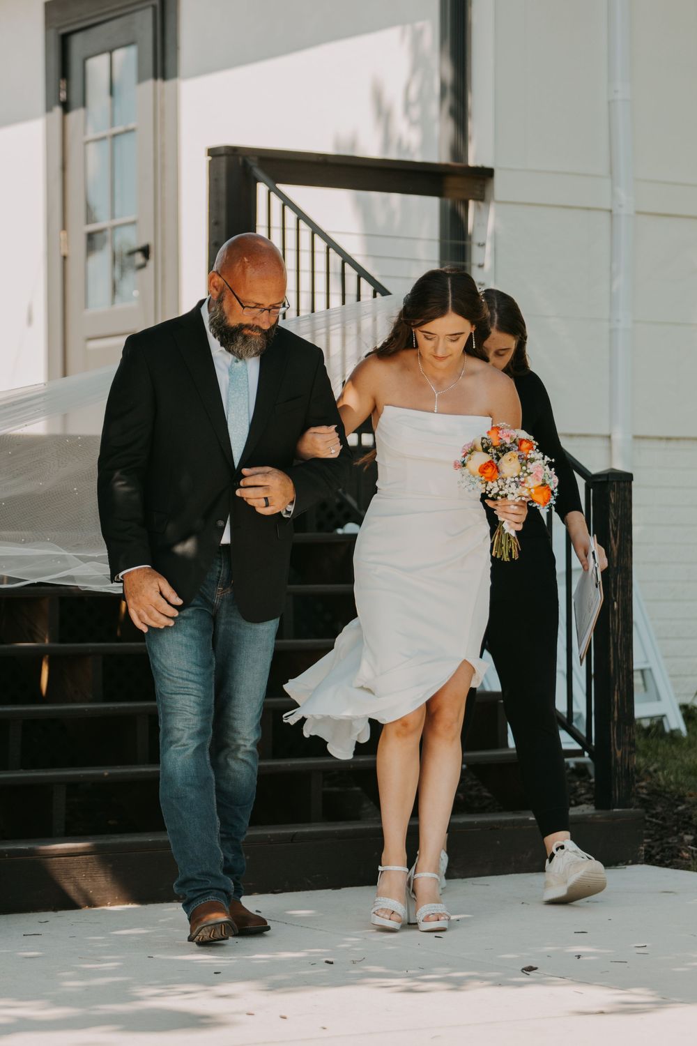 A sequence of four photos showing a person in white dress and another in black blazer walking together down stairs.