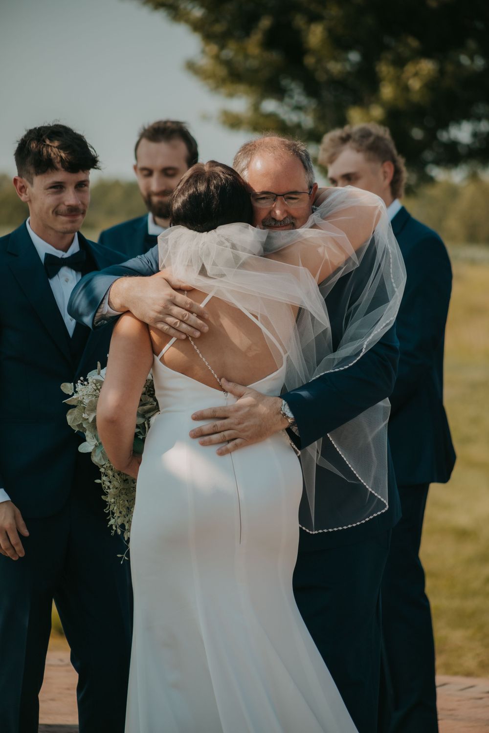 An emotional embrace between wedding participants during an outdoor ceremony.