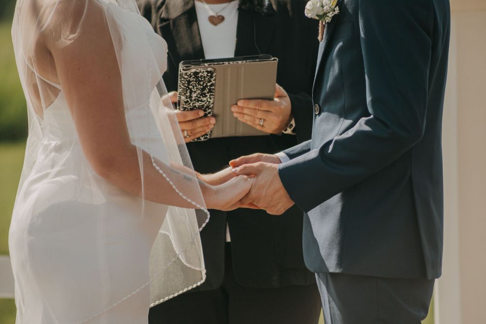 Close-up of hands holding a ceremony program during an outdoor wedding.