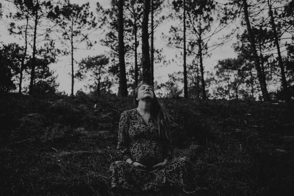 foto preto e branco na floresta  de grávida com a mão na barriga em sessão fotográfica de gestantes em Alcobaça Portugal