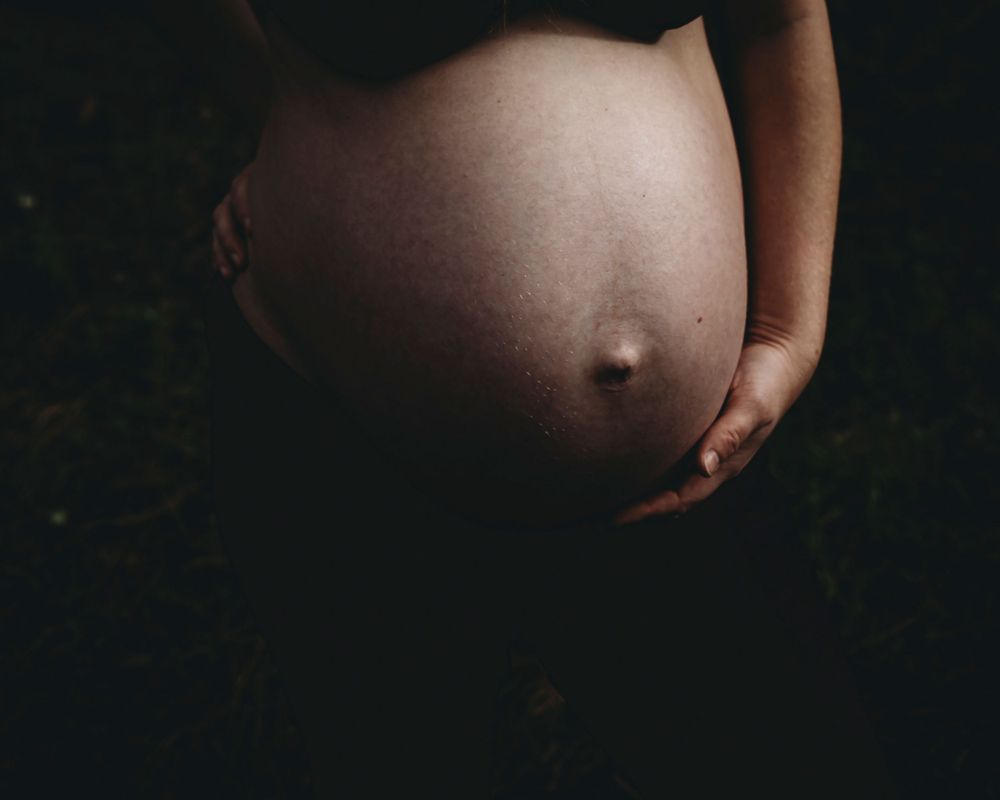 detalhe da barriga de grávida em foto colorida luz dura, durante sessão fotográfica de gestante em Alcobaça