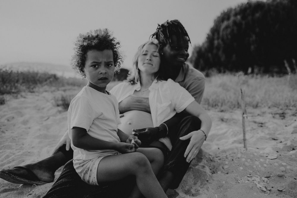 sessão de grávida Caldas Da Rainha, foto da mãe grávida com o pai que abraça e a filha mais velha , fotos gestante preto e branco