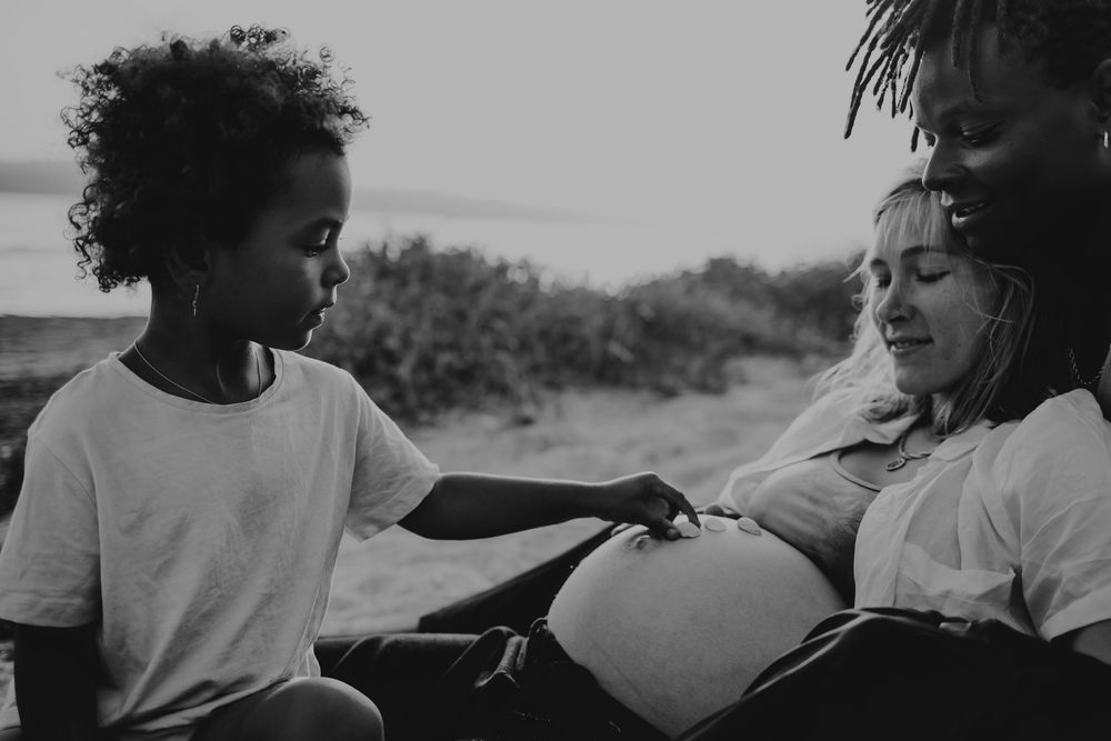sessão de grávida Caldas Da Rainha, foto da mãe grávida com o pai que abraça e a filha mais velha , fotos gestante preto e branco