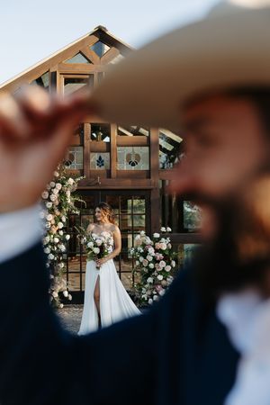 Wedding ceremony setup with floral arch and decorative elements in rustic indoor venue.
