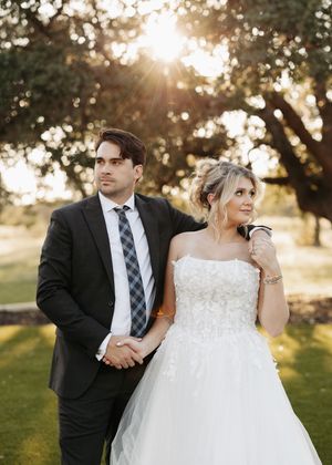 A romantic moment between newlyweds during golden hour with oak trees creating a dreamy backdrop.