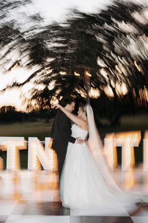 Motion blur captures a romantic dance between newlyweds on their wedding day with glowing lights in the background.