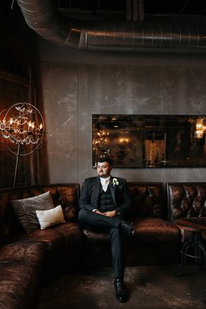 A moody indoor setting with dark furniture and warm lighting creates an intimate atmosphere for a formal occasion.