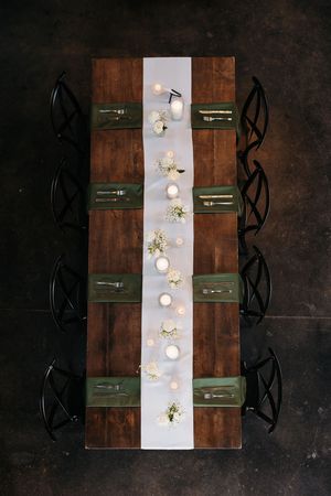 Overhead view of modern restaurant tables with white runners, green placemats, and minimalist table settings.