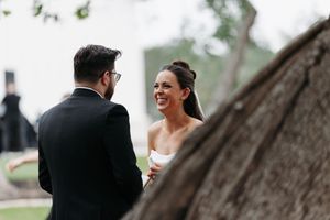 Bride and groom sharing a joyful moment outdoors during their wedding ceremony near a rustic tree.