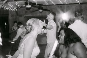 Black and white photo of wedding guests dancing joyfully at a reception party.