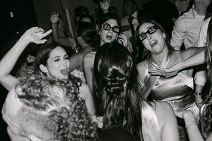 Women dancing at a New Year's Eve party wearing 2019 glasses in black and white photo.