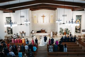 Interior view of a modern church sanctuary with exposed wooden beams and white walls during a service.