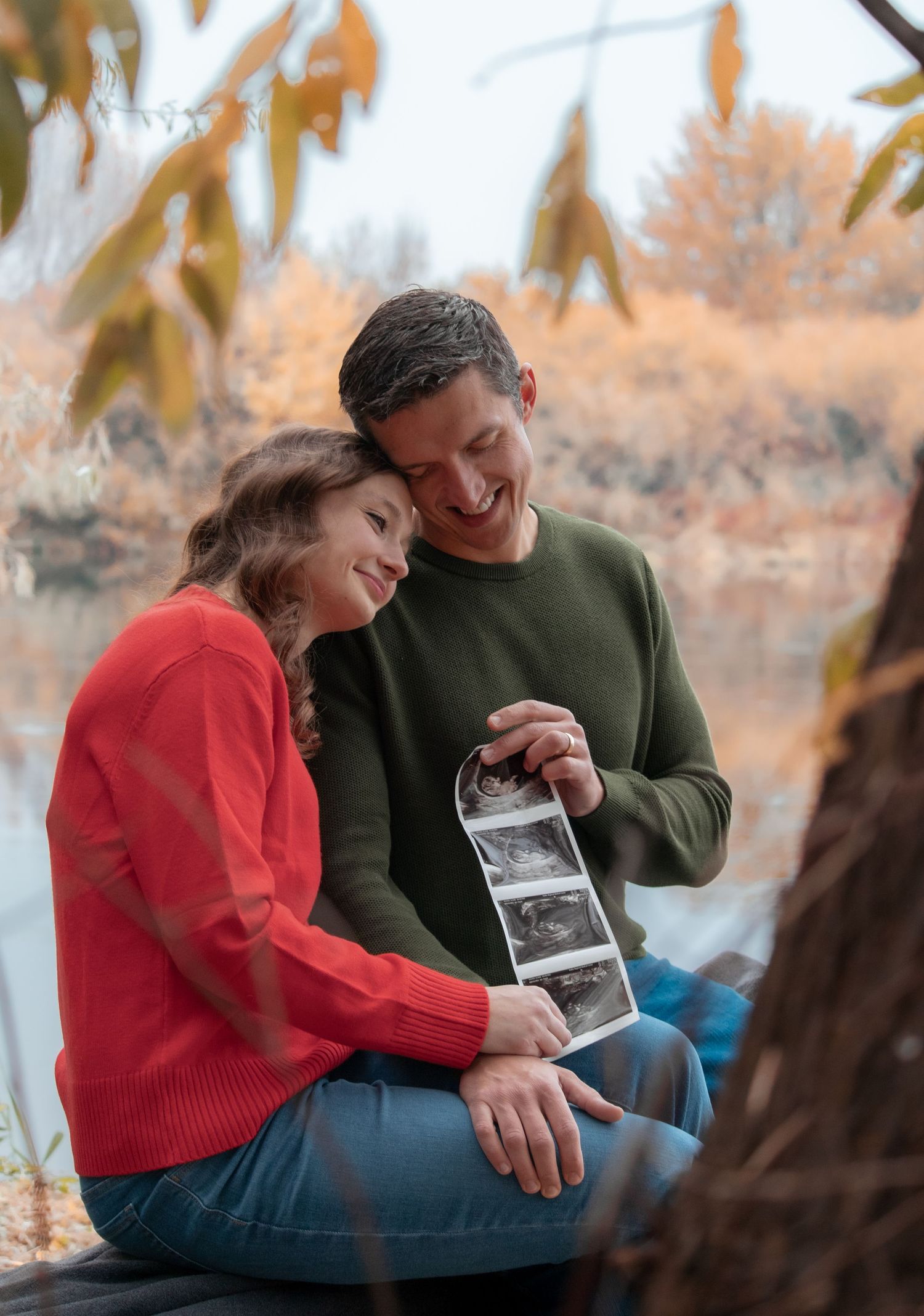 Couple sitting together and holding a sonogram during a cozy fall pregnancy announcement session in Tri-Cities WA