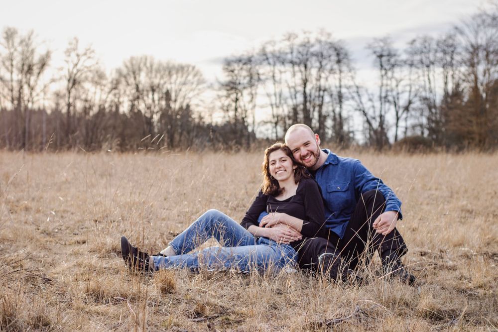 a man and woman sit together in a vast, golden field and smile at the camera.