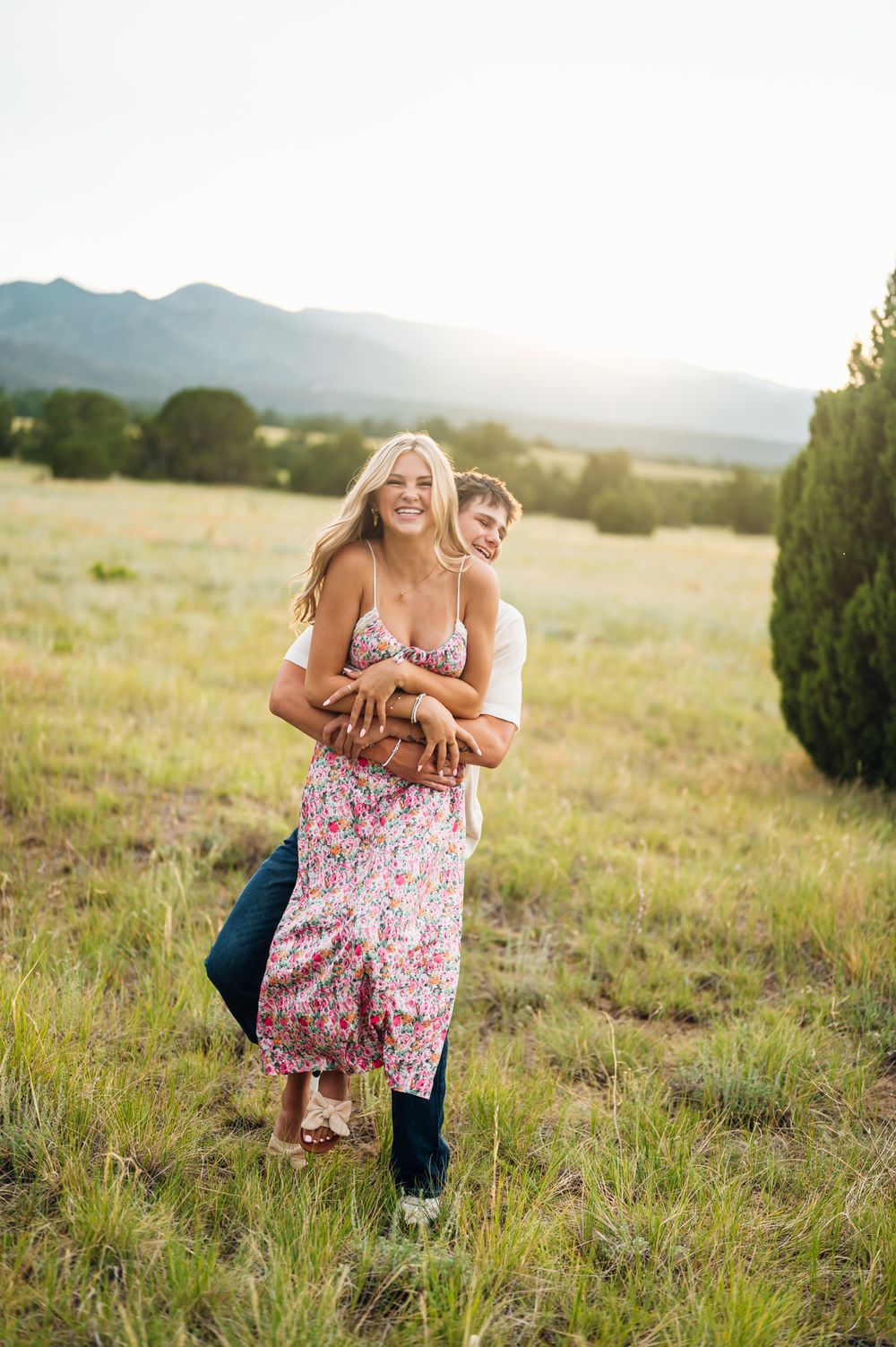 Collage of four romantic outdoor portraits showing couple laughing and embracing in a scenic mountain meadow at sunset.