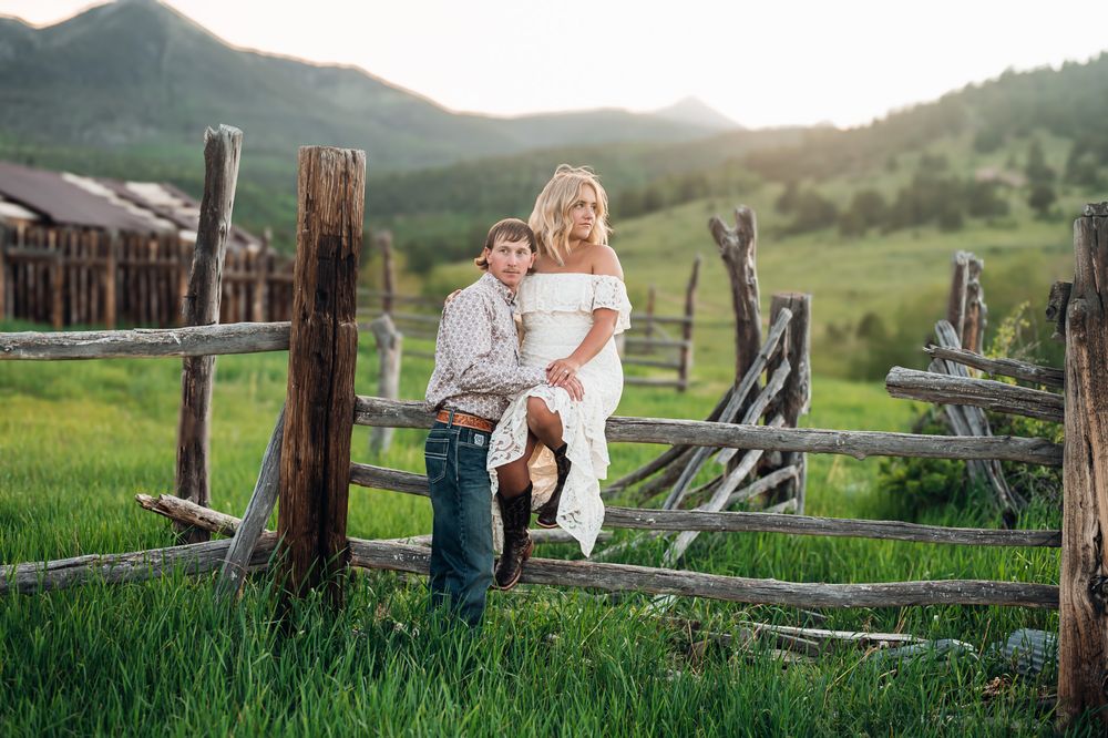 Family portrait session in a rustic mountain field with wooden fencing during golden hour.