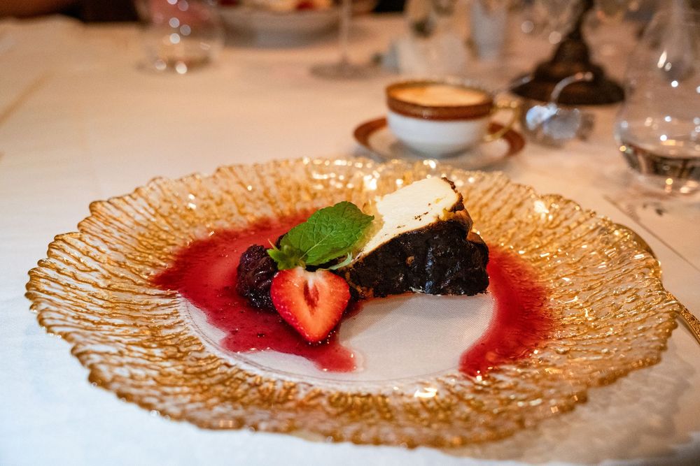 Elegant glass dessert plates with berries and white cream displayed on a formal dining table setting.