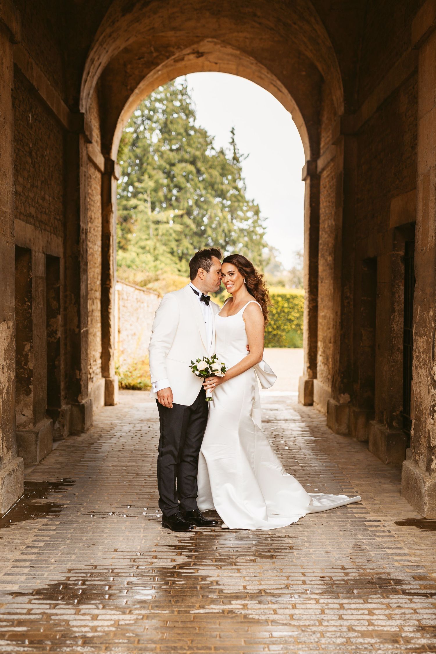 elegant bride and groom under archway smiling and in love