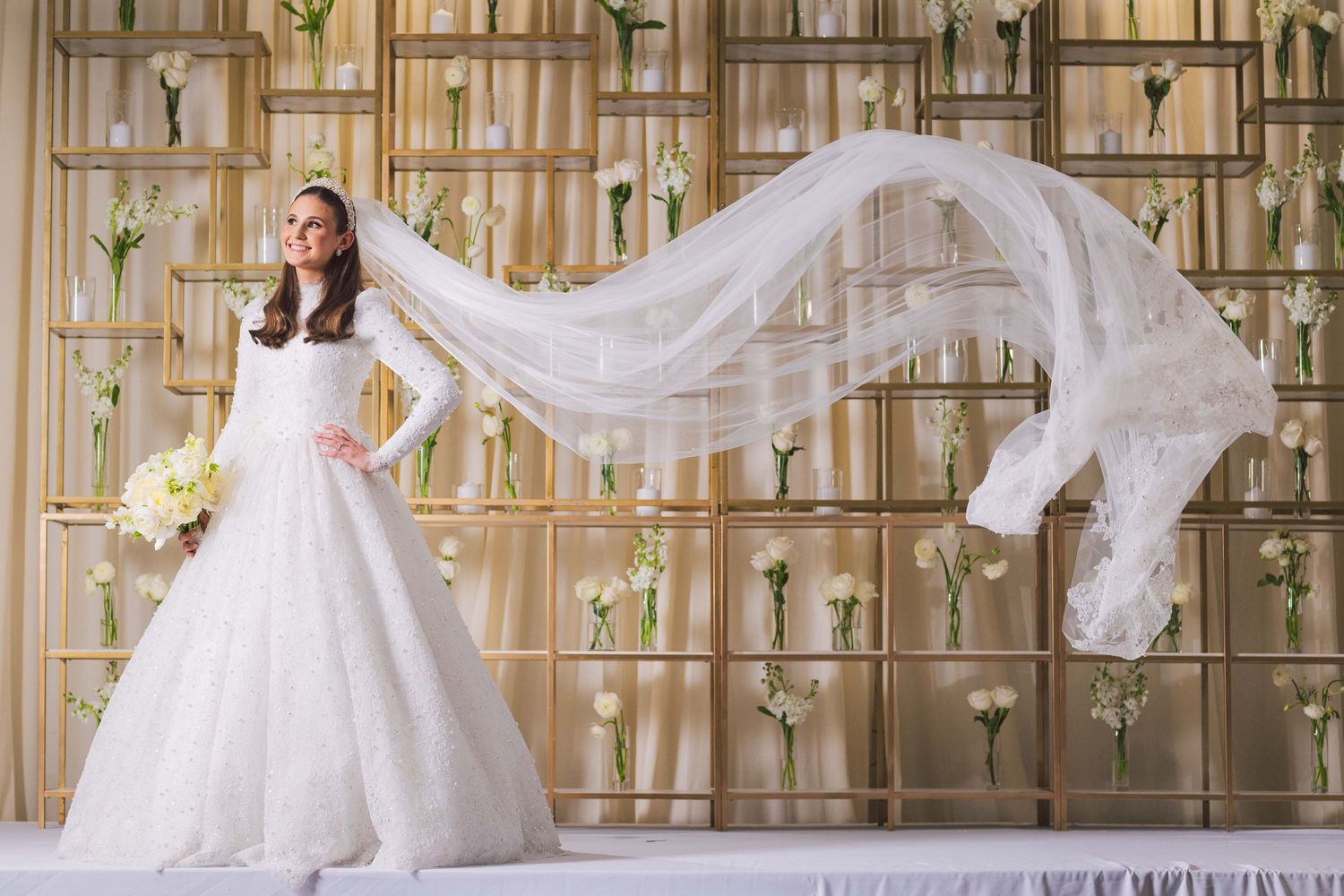 Elegant bridal dress displayed in ornate gold and cream colored venue setting.