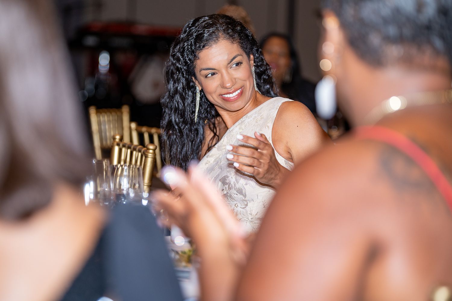 Guest enjoying conversation at formal dinner event with elegant table settings.