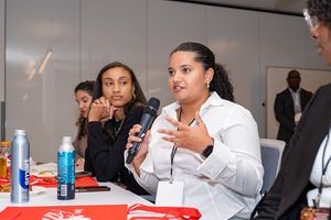 Panel discussion participants seated at table with microphones and water bottles.