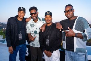 Four friends pose together at a rooftop event against a cityscape backdrop.