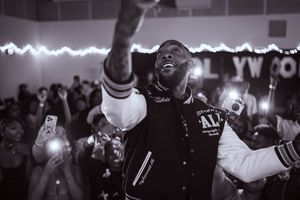 Energetic performer on stage with crowd cell phones lighting up the background.