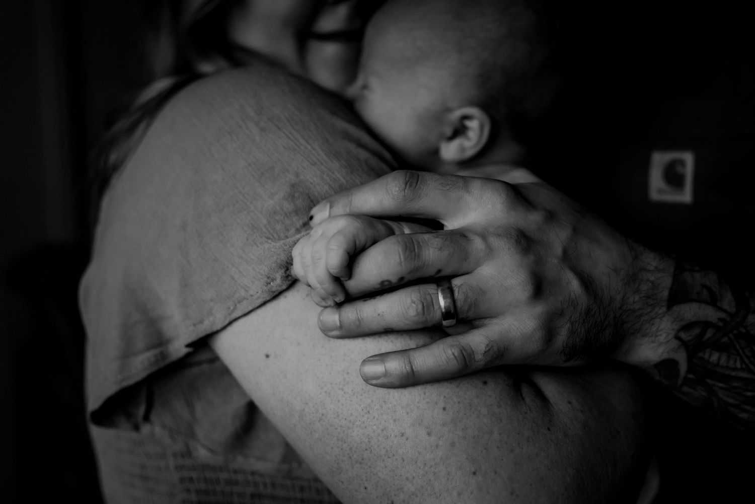 Black and white close-up of hands tenderly holding a sleeping baby.