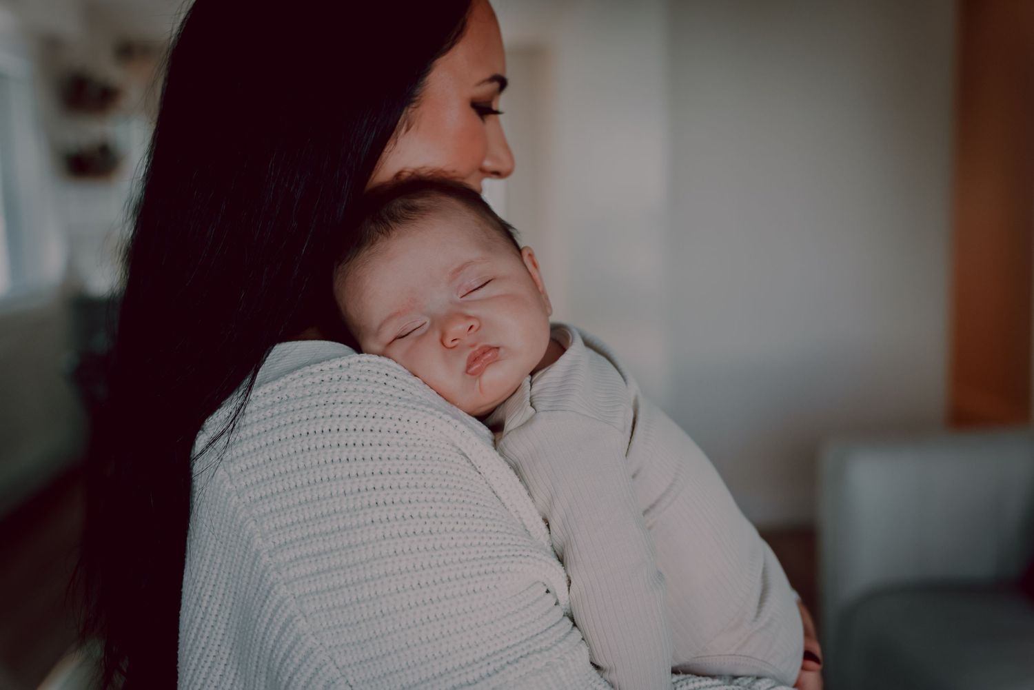 A tender moment showing a sleeping baby being held in soft, ambient lighting.