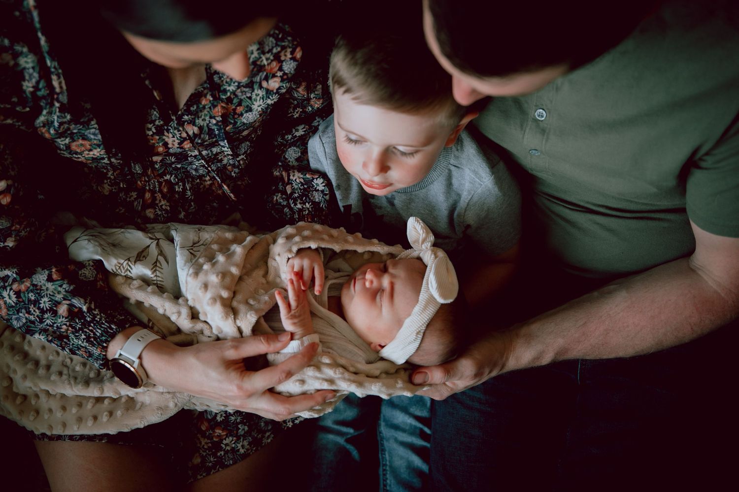 Family gathers around to look at newborn baby.