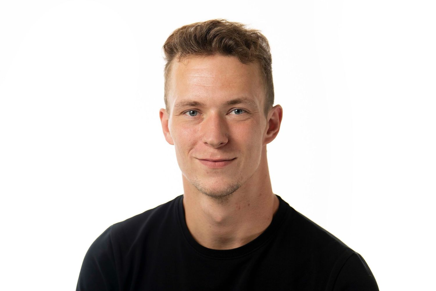 Young smiling man with short blonde hair wearing a black t-shirt against a white background.