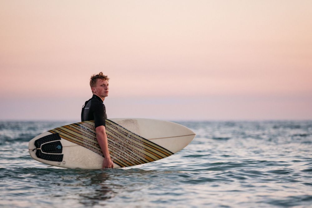 Fort Walton Beach Senior portraits lifestyle shoot at the boardwalk during sunset. Surfing photoshoot at the Boardwalk on Okaloosa Island FL