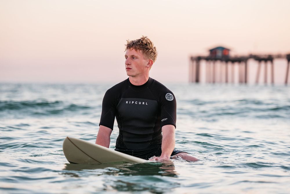 Fort Walton Beach Senior portraits lifestyle shoot at the boardwalk during sunset. Surfing photoshoot at the Boardwalk on Okaloosa Island FL