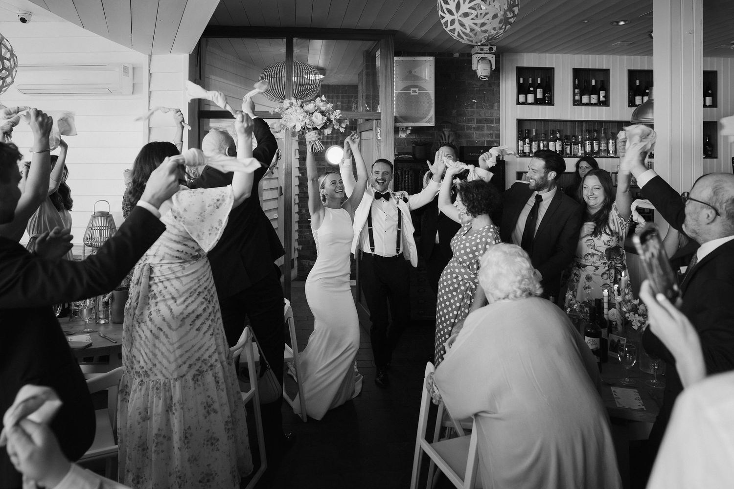 Wedding guests cheering Bride and grooms entrance to wedding breakfast at tunnels beach wedding venue in north devon